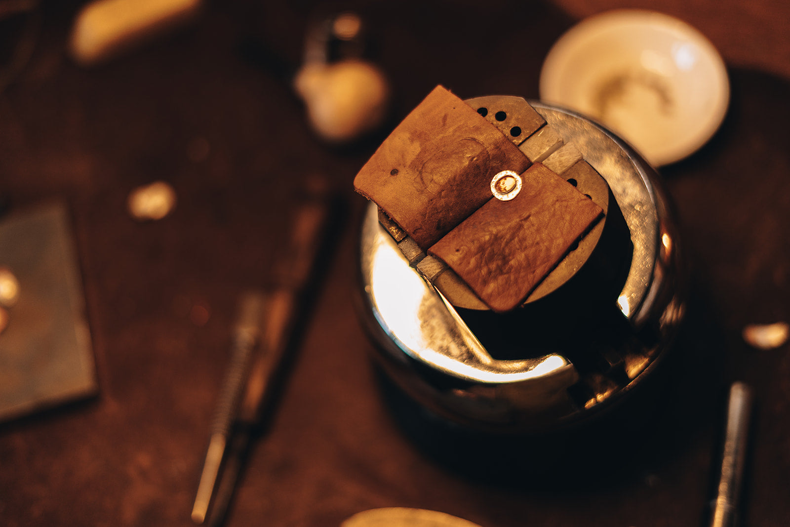 Close-up of a metal container with a leather cover on a wooden surface.